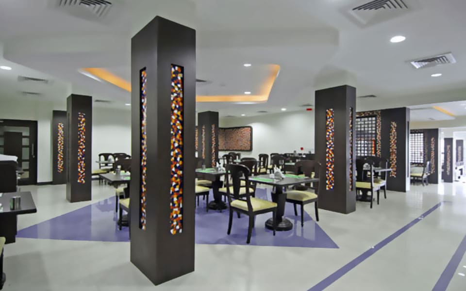Dining room with espresso columns inlaid with backlit mosaic and a lavender inlay set into glossy ivory tiling