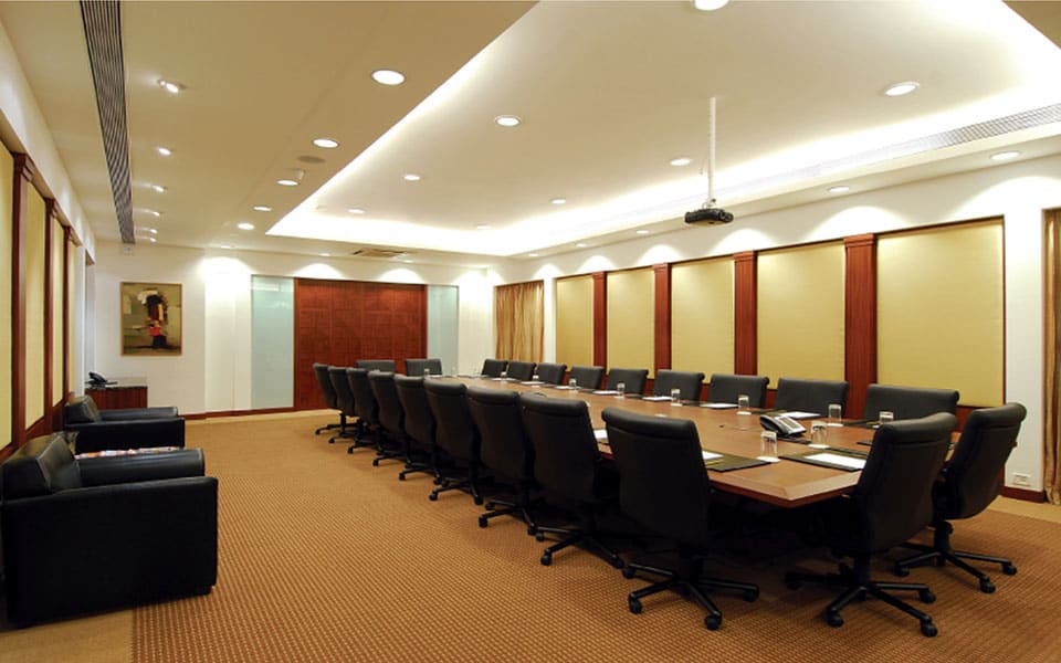 Boardroom with long veneer table, black leather chairs, fabric wall panels and a stepped cove-lit gypsum ceiling