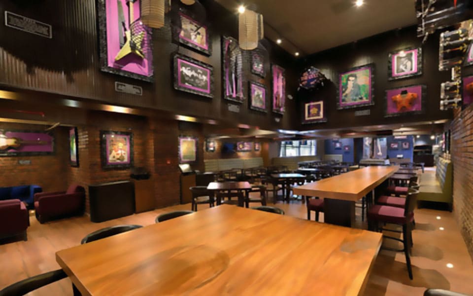 Double-height memorabilia wall above brick and a long communal timber table with high stools