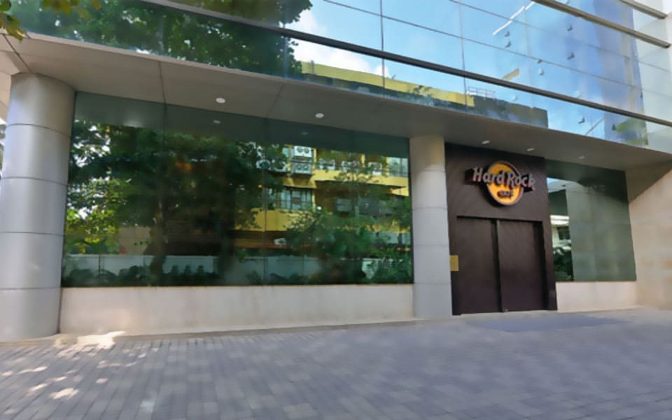 Hard Rock Cafe entrance portal in dark timber under a glass curtain wall, with stone-clad columns