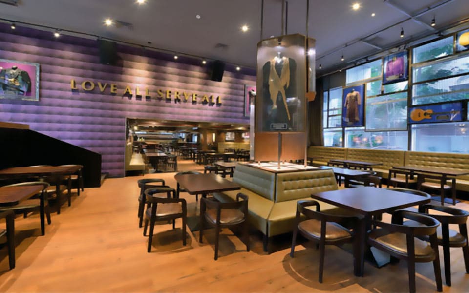 Dining floor with olive tufted banquettes, a glazed memorabilia column and gold wall lettering