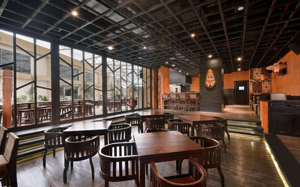 Dining room with slat-back timber chairs, black steel glazing and an open-cell metal grid ceiling