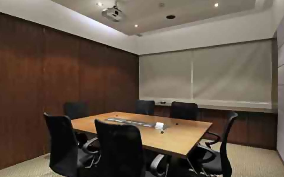 Boardroom with a maple laminate table, black mesh chairs, walnut panelled walls and a ceiling-mounted projector