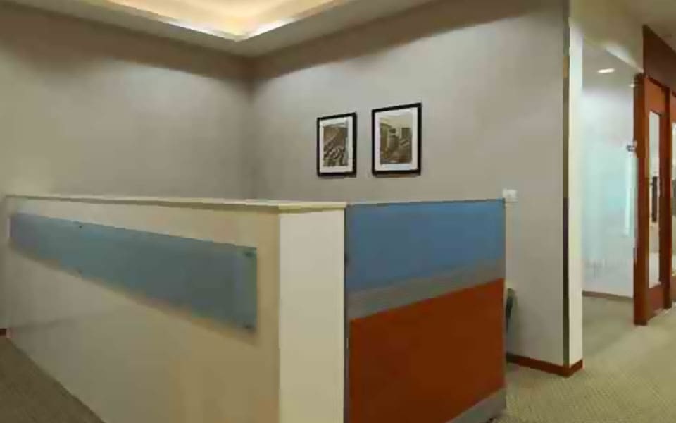 Circulation corridor beside low workstation screens in blue and terracotta fabric under a coved gypsum ceiling