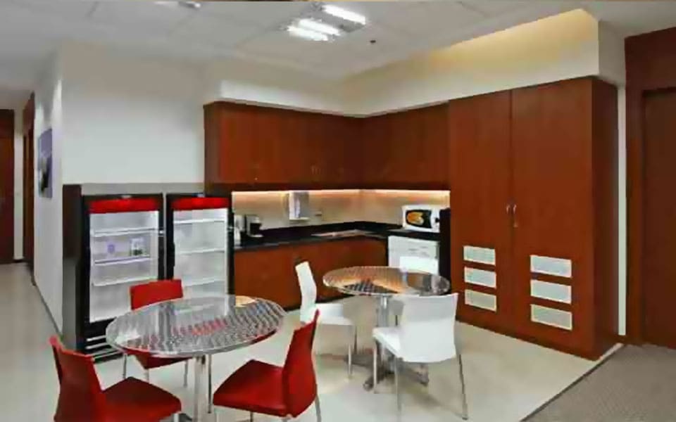 Staff pantry with cherry veneer wall units, black granite counter, glass-front coolers and steel pedestal tables