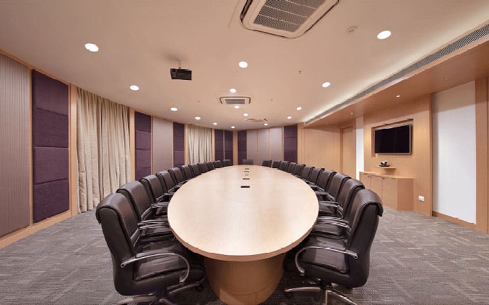 Boardroom with oval maple veneer table, black leather chairs, aubergine fabric wall panels and cove-lit ceiling