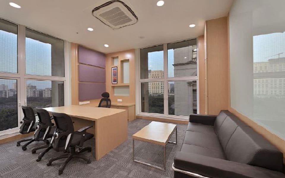 Corner cabin with maple veneer desk, mauve fabric wall panel, leather sofa and full-height corner glazing