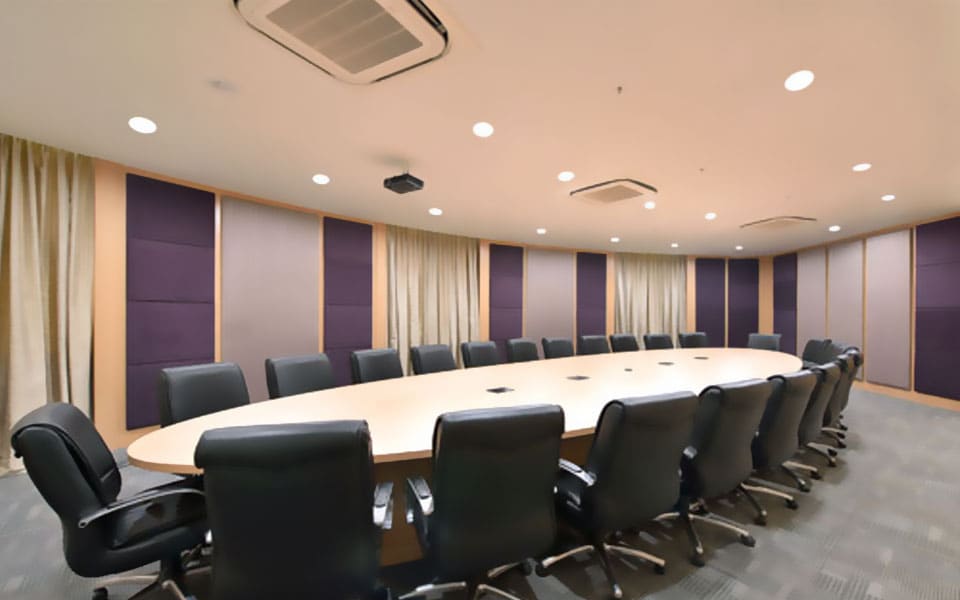 Boardroom with a long oval maple table, black leather chairs and aubergine upholstered acoustic wall panels