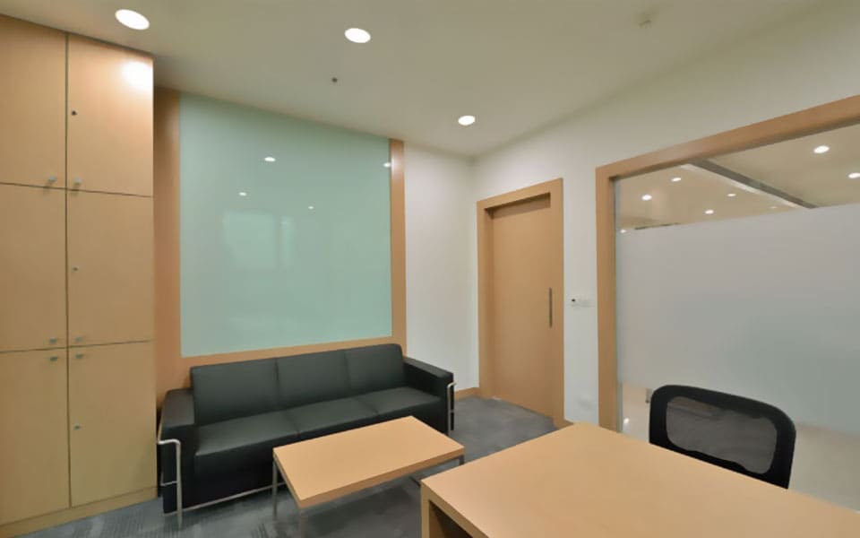 Cabin with a full-height maple storage unit, back-painted green glass panel, dark sofa and low timber table