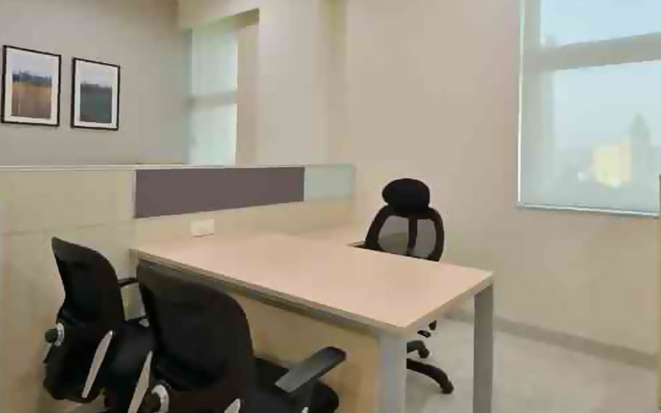 Small cabin with a light laminate L-shaped desk, grey screen and framed prints beside a window