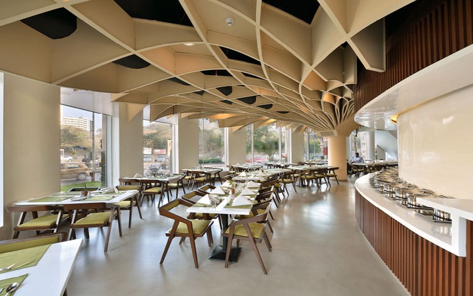 Dining room along a glazed elevation with the ribbed ceiling canopy overhead and the buffet counter at right