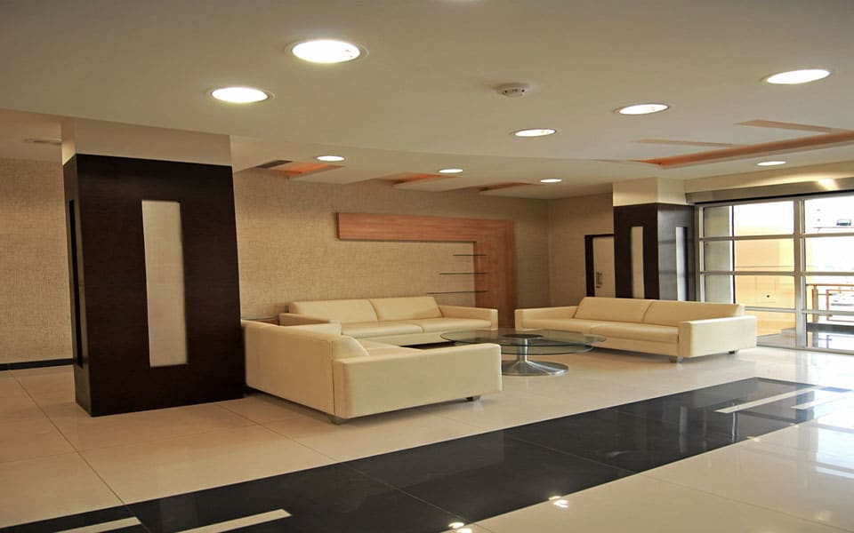 Lobby lounge with cream leather sofas, a round glass table and wenge columns holding lit glass niches