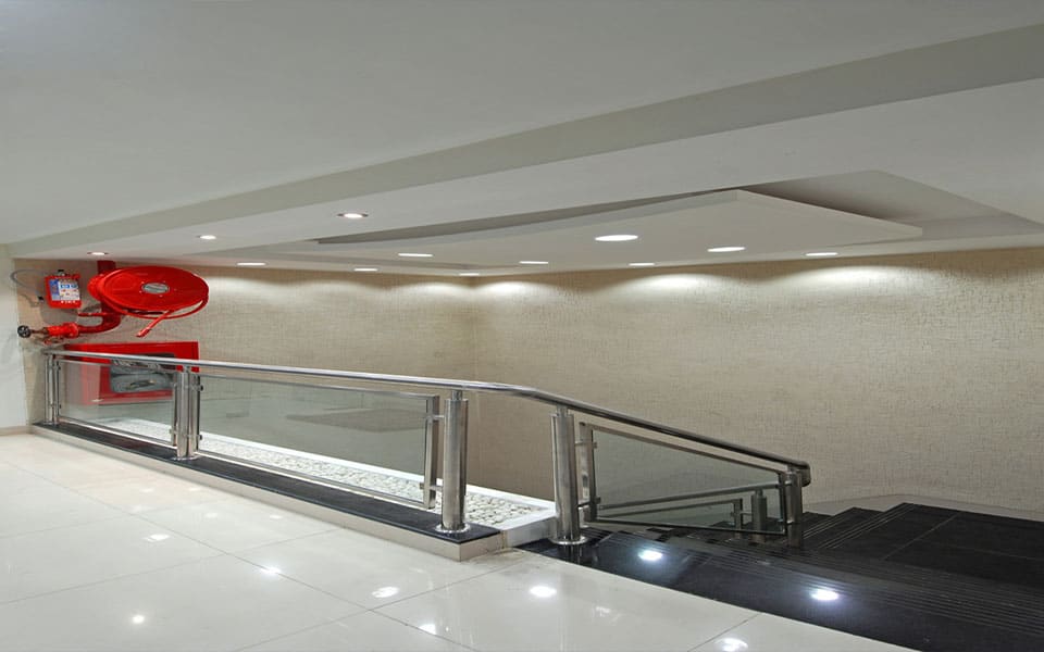 Stair landing with a stainless steel and glass balustrade, pebble trough and textured cream wall